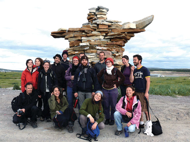 UQAM students in front on a big inukshuk (stone monument) in the North.