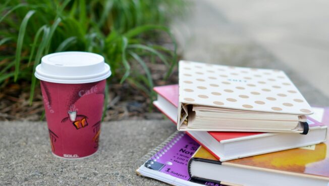 A clips of shot of a stack of books and a coffee cup taken outdoors