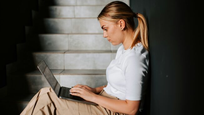 A young woman working on a laptop in a stairwell